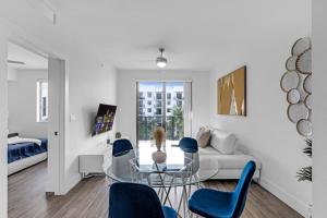 - un salon avec une table en verre et des chaises bleues dans l'établissement Sleek Doral Retreat 1 Bed Oasis With Free Parking, à Hialeah Gardens