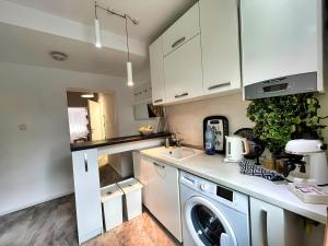 a kitchen with white cabinets and a washer at Sal Apart in Timişoara