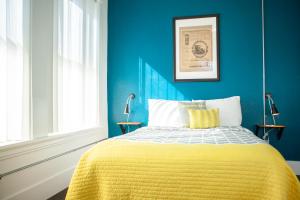 a blue bedroom with a bed with a yellow blanket at 11th Avenue Hostel in Denver