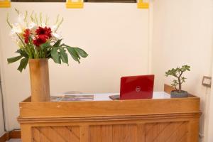 a desk with a laptop and flowers on it at Hotel Los Manantiales in Panajachel