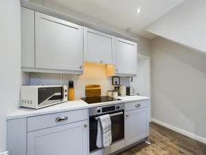 a kitchen with white cabinets and a microwave at Mill House, Belfast City Centre in Belfast