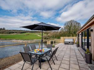 a table and chairs with an umbrella on a patio at 2 Bed in Castle Douglas 77838 in Auchencairn