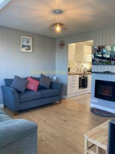a living room with a blue couch and a kitchen at Cosy 2 Bed Chalet in Great Yarmouth