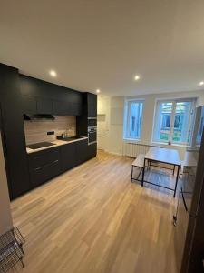a large kitchen with a wooden floor and black cabinets at Appartement Saint-Etienne hyper centre in Saint-Étienne