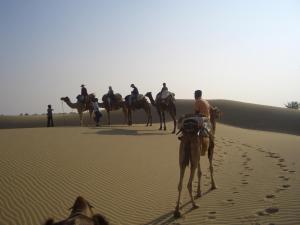 a group of people riding camels in the desert at Shahi Palace Hotel Jaisalmer in Jaisalmer