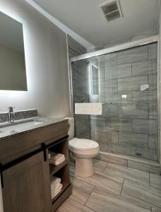 y baño con aseo, lavabo y ducha. en Days Inn and Suites by Wyndham Port Huron en Port Huron