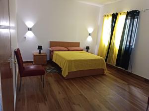 a bedroom with a bed with a yellow bedspread and a chair at Espaço-Vila Verde 