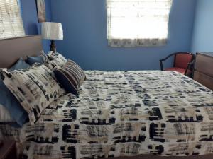 a blue bedroom with a bed with a comforter and pillows at Beautiful St Pete Beach, FL 2nd Floor 2BR Unit in St. Pete Beach