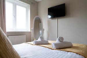 1 dormitorio con 1 cama con toallas y espejo en Entire 4 Bed Cosy Luxury Spacious house, en Huntingdon