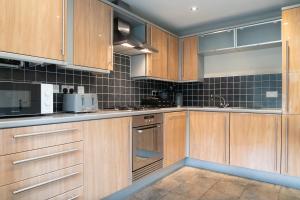 a kitchen with wooden cabinets and appliances at Entire 4 Bed Cosy Luxury Spacious house in Huntingdon