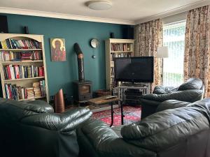 a living room with a leather couch and a television at Lowry House Hotel in Walsall in Birmingham