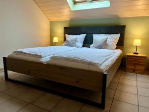 a bedroom with a large bed with white sheets and pillows at Ferienapartments Eifel Stay in Lissendorf