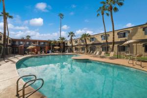 duży basen z krzesłami i palmami w obiekcie Quality Inn & Suites Goodyear - Phoenix West w mieście Goodyear