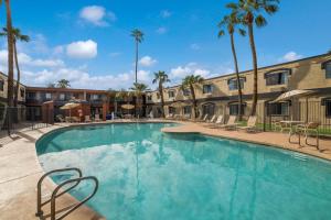 a large swimming pool with chairs and palm trees at Quality Inn and Suites Goodyear in Goodyear