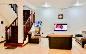 uma sala de estar com um sofá e uma televisão de ecrã plano em Lihini Scandic Bungallow em Ganepola