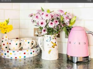 a kitchen counter with a vase of pink flowers at Piglet Cottage in Pebworth