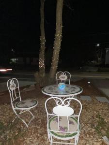 twee stoelen en een tafel voor een boom 's nachts bij Mel-C's Cozy Cottage in Monroe