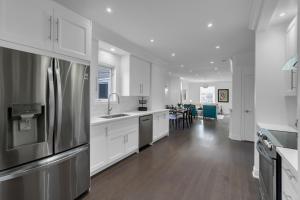 a kitchen with white cabinets and a stainless steel refrigerator at Luxury 4BR - Free Parking - 10 Minutes to Downtown in Toronto