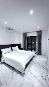 a white bedroom with a large bed and a window at MantaSurf Hotel in Tarqui