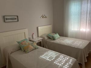 2 camas individuais num quarto com uma janela em Luxury Hacienda Golf Islantilla em Islantilla