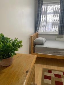 Schlafzimmer mit einem Bett, einem Fenster und einem Tisch in der Unterkunft Goodmayes Park Home in Goodmayes