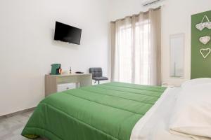 un letto verde in una camera bianca con televisore di Case Billeci Casa Verde a Palermo Altre 8 foto