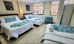 una camera d'albergo con due letti e un divano di Hotel Virgen del Cisne a Loja