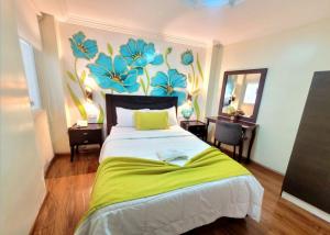 a bedroom with a bed with a flower mural on the wall at Hotel Virgen del Cisne in Loja