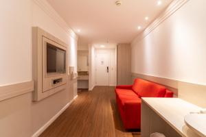 a living room with a red couch and a television at BSB STAY TORRE - FLATS PARTICULARES - SHN in Brasilia