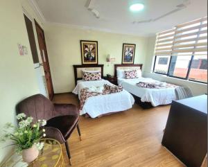 una camera con due letti e una sedia di Hotel Virgen del Cisne a Loja