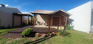 a wooden deck in front of a house at Linda casa com piscina 50m praia in Arroio do Sal