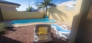 a small swimming pool with two chairs and a table at Linda casa com piscina 50m praia in Arroio do Sal