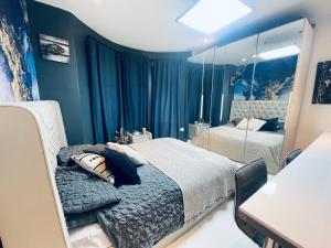 een blauwe slaapkamer met een bed en een spiegel bij Unique and Artsy Holiday Shared Home in Purley