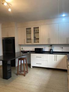 uma cozinha com armários brancos, uma mesa e um banco em The ranch apartments, en-suite rooms em Lusaka