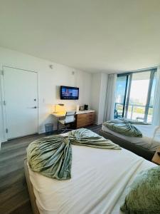 1 dormitorio con 2 camas, escritorio y TV en Lovely 2Bed 1Bath Condo With Private Balcony 18th Floor, en Hallandale Beach