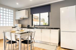 a kitchen with white cabinets and a table and chairs at Casa dos Anjos, a Home in Madeira in Faial +23 photos