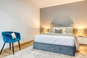 um quarto com uma cama e uma cadeira azul em Casa dos Anjos, a Home in Madeira no Faial