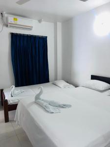 two beds in a room with a blue curtain at HOTEL COLONIAL in Barrancabermeja