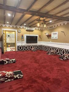 a room with a red carpet and a flat screen tv at منتجع لامة مدر in Al Wudayy