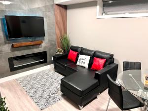 a living room with a black leather couch with red pillows at Niagara Getaway across Fallsview in Niagara Falls