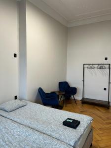 a bedroom with a bed and two blue chairs at Kopernik Premium Rooms Apartment in Toruń