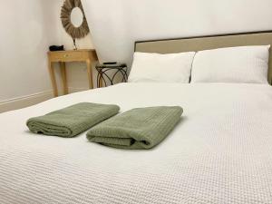 a bed with two green towels on top of it at Soho Apartments in London