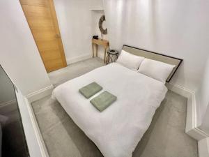 a white bed with two green towels on it at Soho Apartments in London