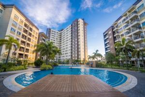 a large swimming pool with palm trees and buildings at Modern Oasis*Heart of City*Fast Wi-Fi/Netflix WFH in Iloilo City