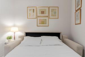 uma cama branca num quarto com fotografias na parede em Sevilla Home Center em Sevilha