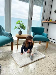 a little girl sitting on a rug in a living room at Miramar, atlantico in Miramar