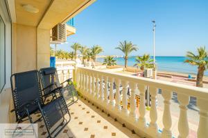 een balkon met een stoel en uitzicht op het strand bij Apartment front line Jakarta 1 Sea View in El Campello +34 foto's