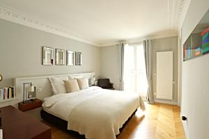 ein Schlafzimmer mit einem großen weißen Bett und einem Fenster in der Unterkunft Luxurious Flat Place Vendome in Paris