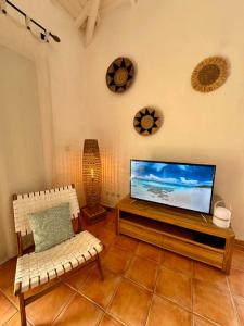 a living room with a flat screen tv and two chairs at Passiflora in Orient Bay