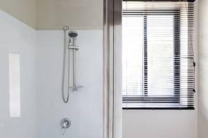 bagno con doccia e finestra con persiane di Funky Heritage Home in the City Center a Launceston Altre 29 foto